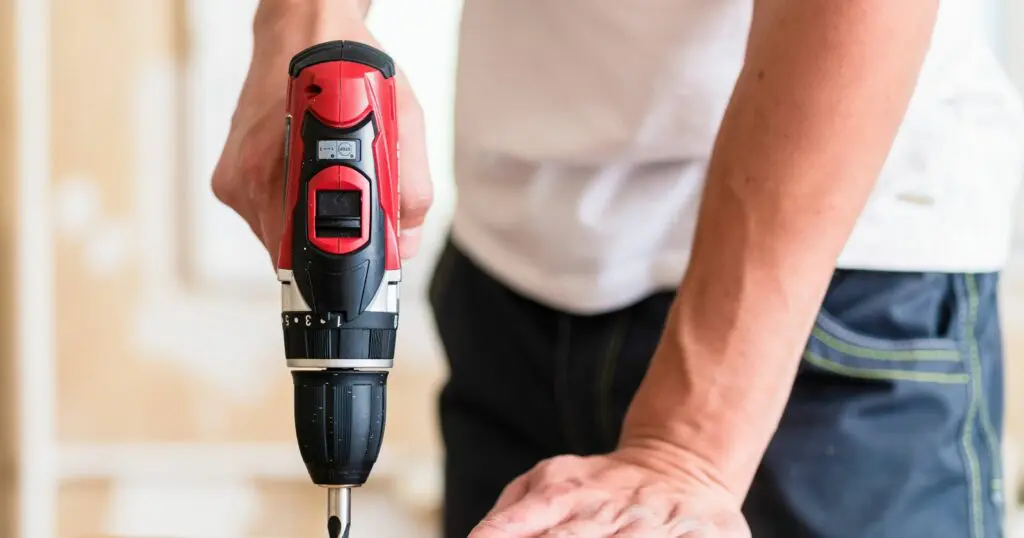 Person using a cordless drill to make a straight hole in a workpiece