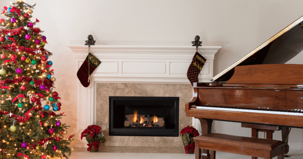 Christmas living room with decorated tree, fireplace, stockings, poinsettias, and piano