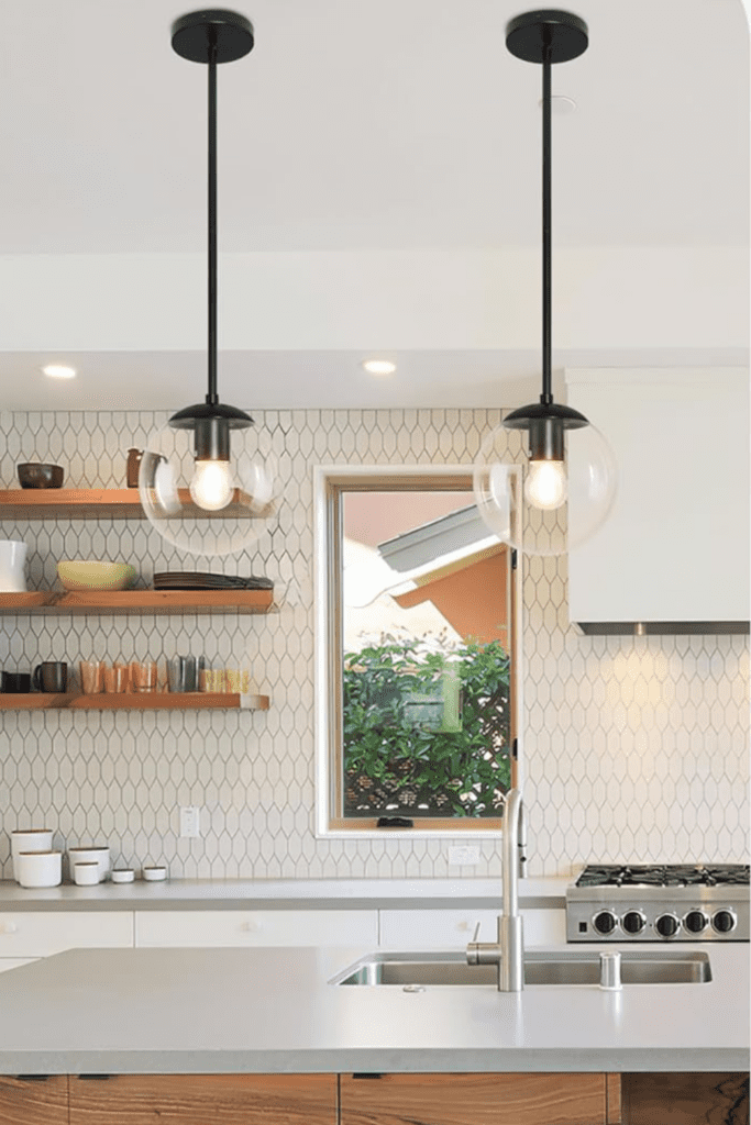 A small kitchen with round globe pendant lights hanging above a kitchen island, featuring bright and cozy lighting.